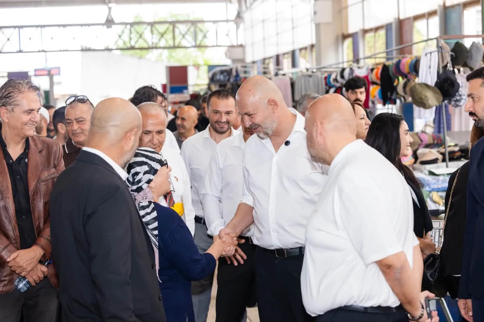 Koral Bozkurt, pazar alanında başörtülü bir kadınla tokalaşırken
