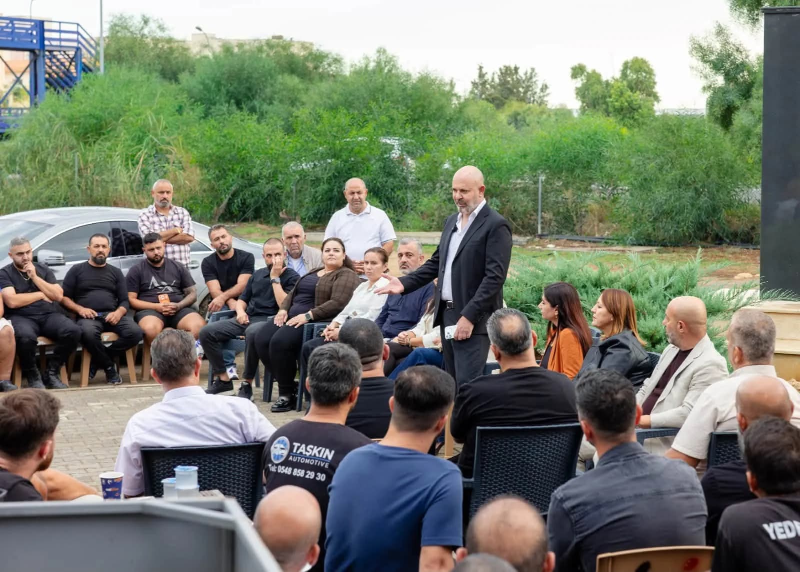 Koral Bozkurt, sanayi bölgesi ziyaretinde ayakta konuşurken, çevresinde oturan esnaf ve sanayiciler