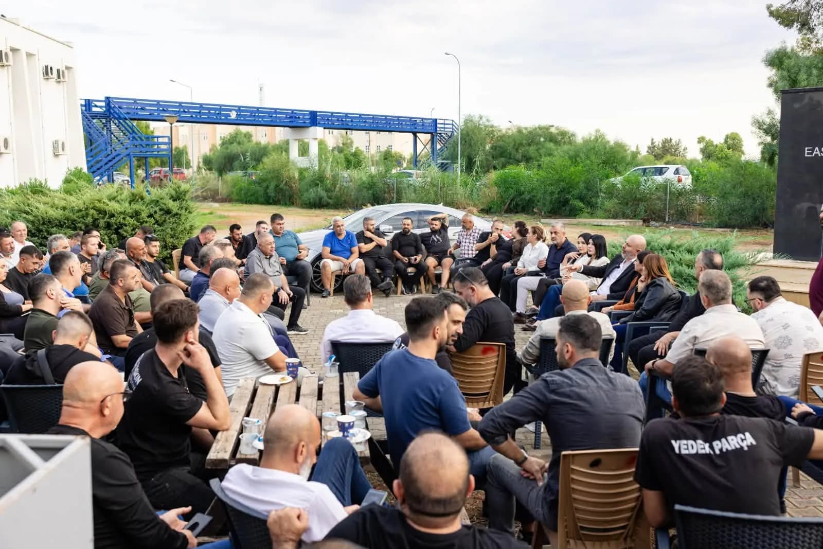 Sanayi bölgesi ziyaretinde açık havada halka şeklinde oturan esnaf ve sanayicilerle toplantı